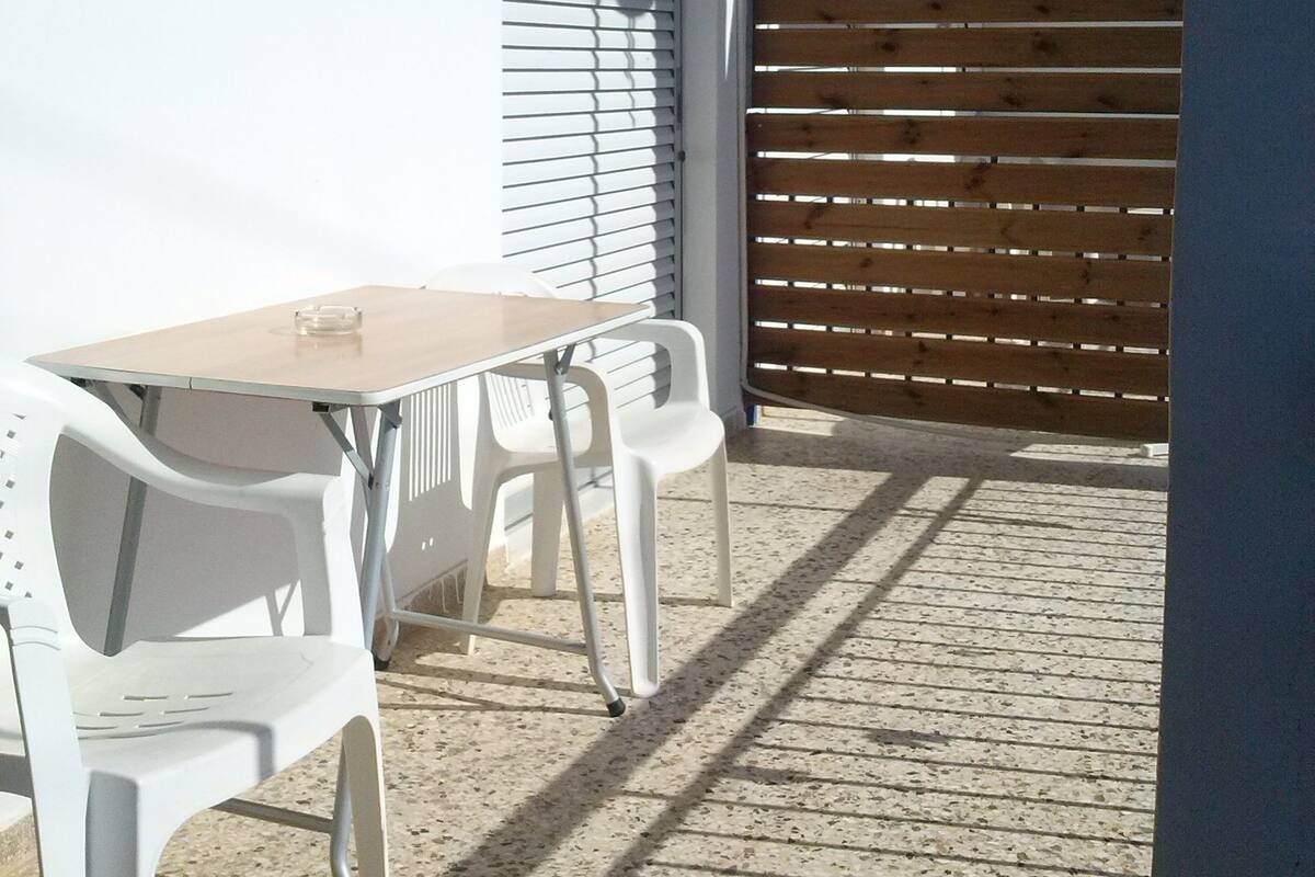 A patio area with a table and chairs, a wooden fence, and an air conditioning unit mounted on the wall.