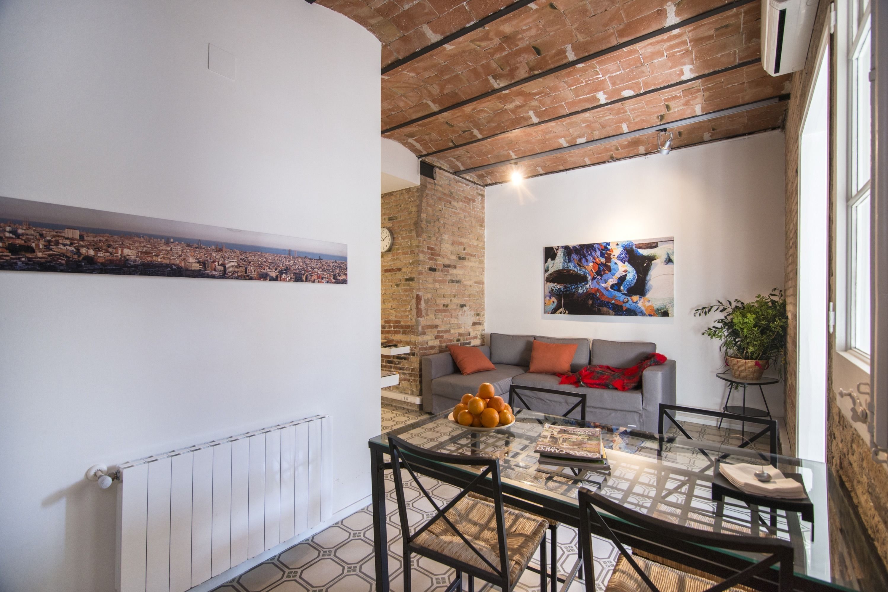 Una sala moderna con una mesa de vidrio, un sofá y vistas a un paisaje urbano.