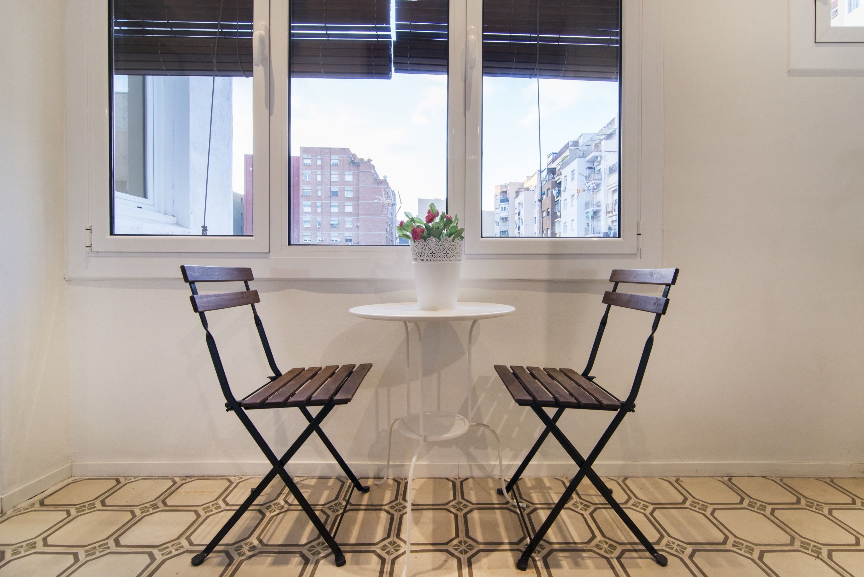 A room with two foldable chairs, a small round table, and a potted plant.