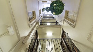 Una scala con ringhiera in metallo, un punto luce a parete e una pianta decorativa.