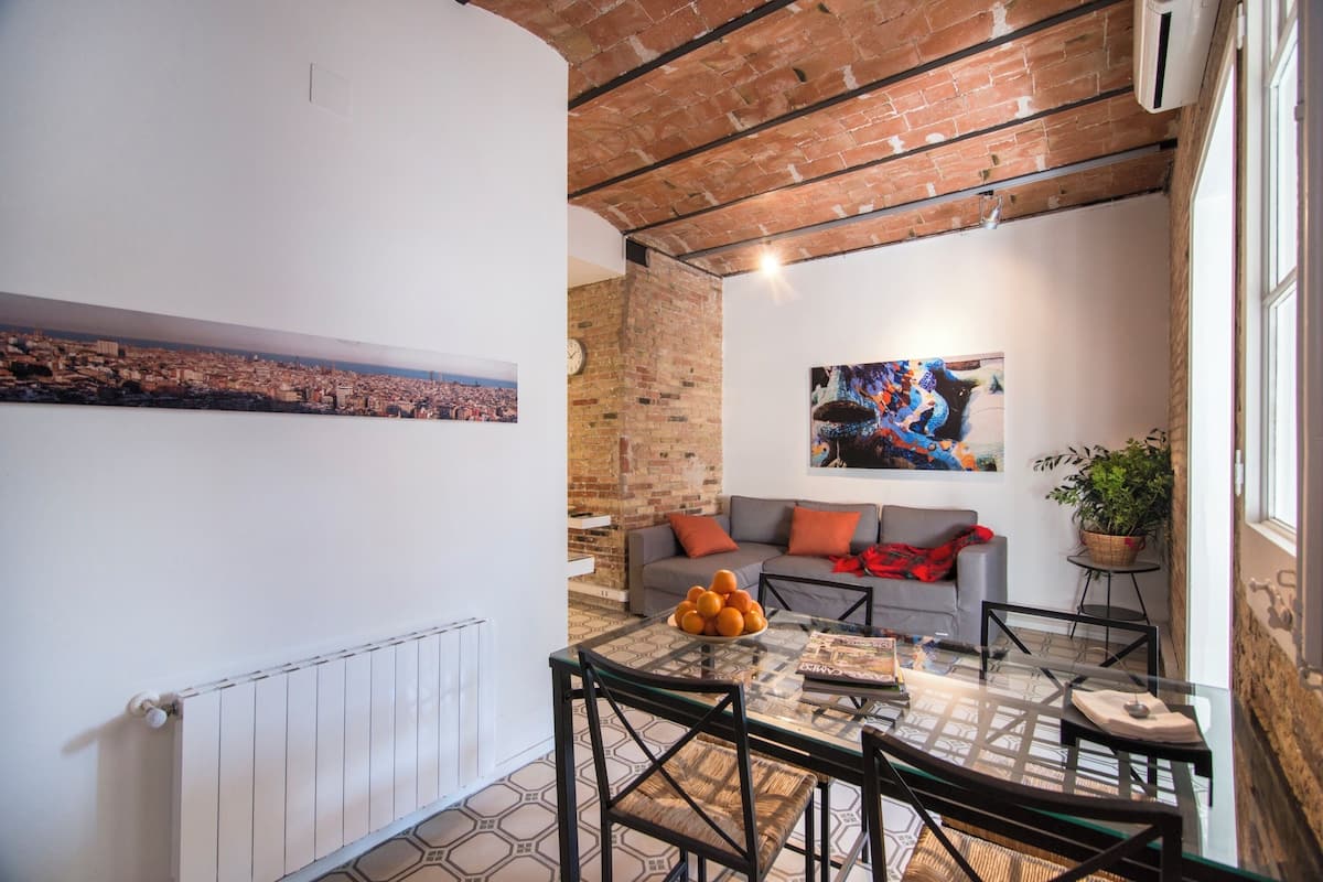 A modern living room with a cityscape view, a dining area with a glass table, and a brick ceiling.