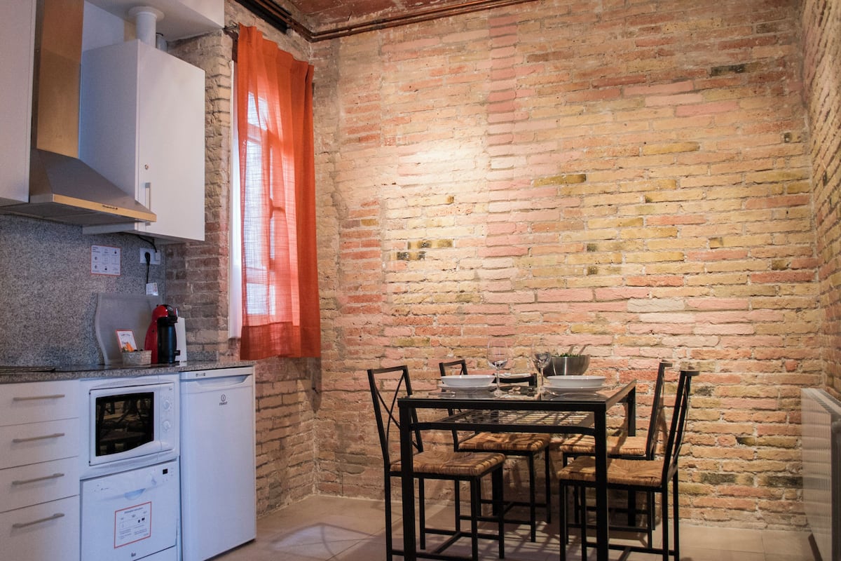 A kitchen with white cabinets, a microwave, and a table set for dining.
