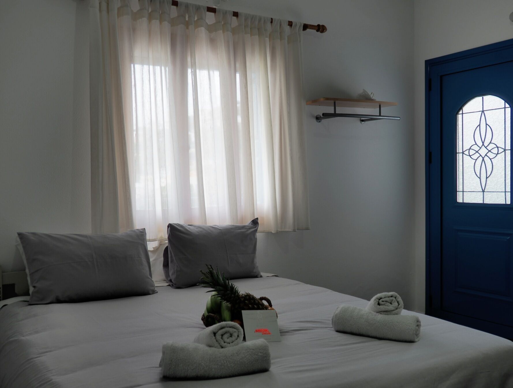 A hotel room with a bed, pillows, a small table with a plant, and a towel on the bed.