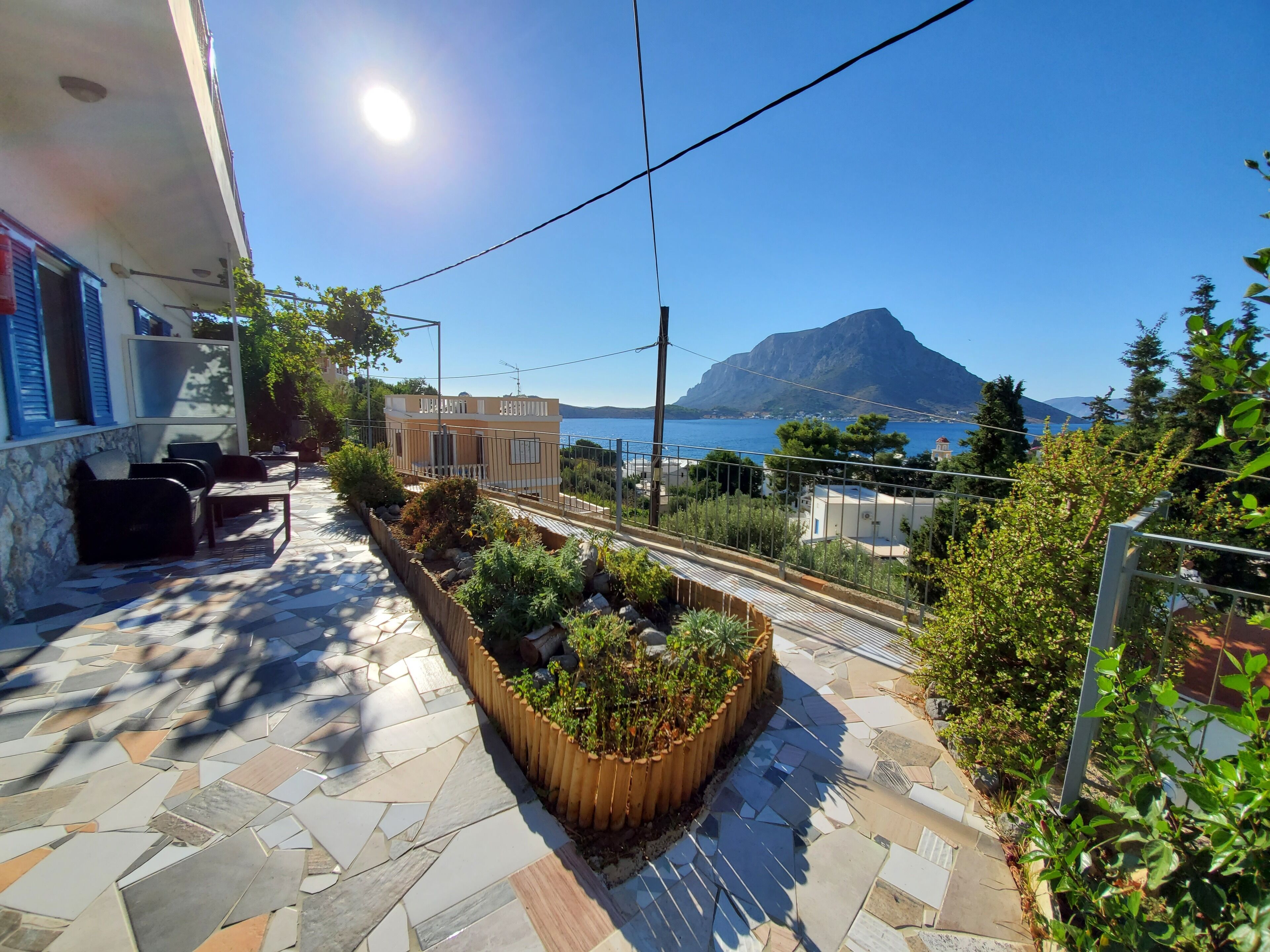 A terrace with stone flooring, outdoor furniture, and a wooden planter with plants.