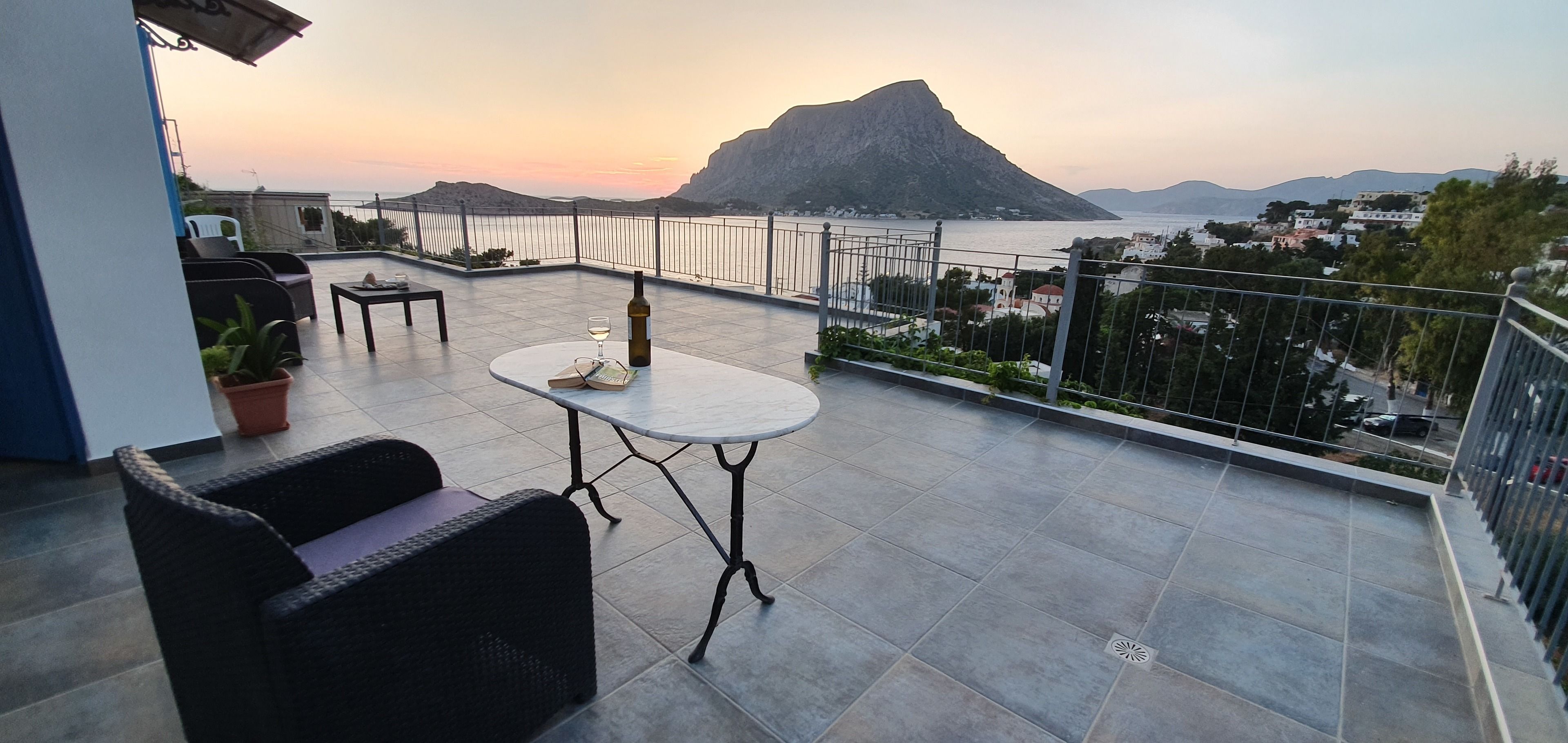 Una terraza con mobiliario exterior, una mesa y una botella de vino.