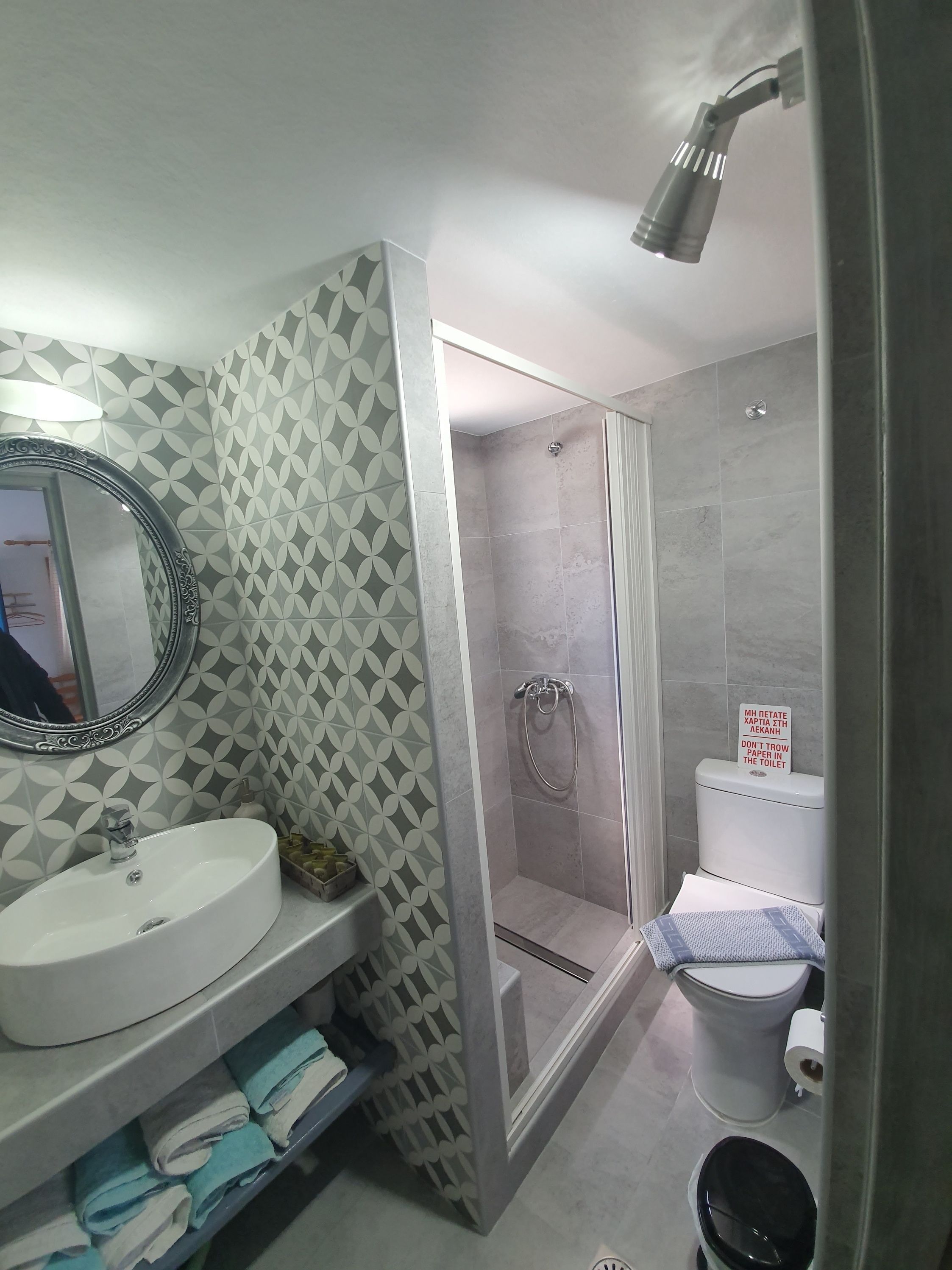 A bathroom with a white sink, a mirror, a shower with a glass door, and a toilet.