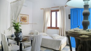 A room with a bed, a table with a plant, and a blue door. - Panorama Studios & Apartments (Kalymnos)