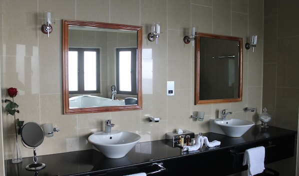 Un baño moderno con dos lavamanos, un espejo grande y un florero con una rosa.