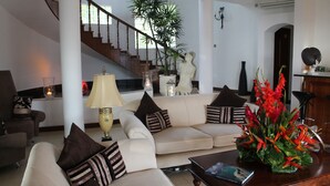 Una sala de estar con un sofá, una mesa de centro, una lámpara y una escalera.