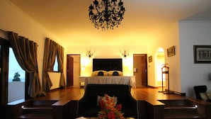 Una habitación de hotel con una cama grande, un rincón de estar con una mesa y una araña.