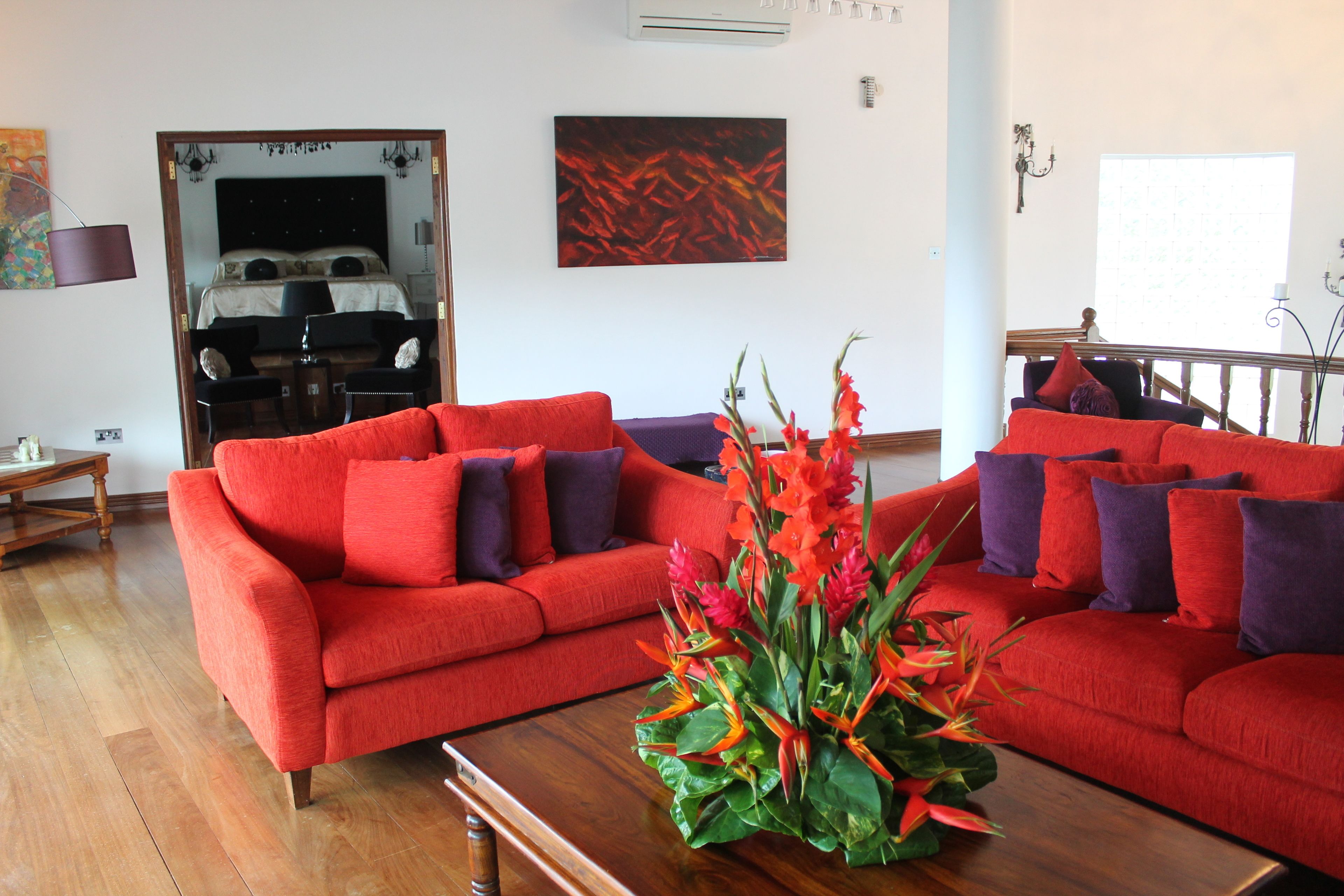 A living room with a red sofa set, a wooden coffee table, and a floral centerpiece.