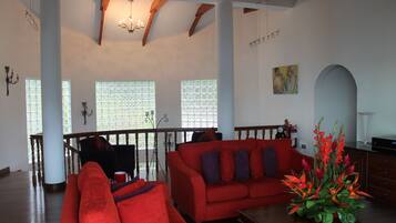A spacious living room with a red sofa, a wooden coffee table, and a decorative plant.