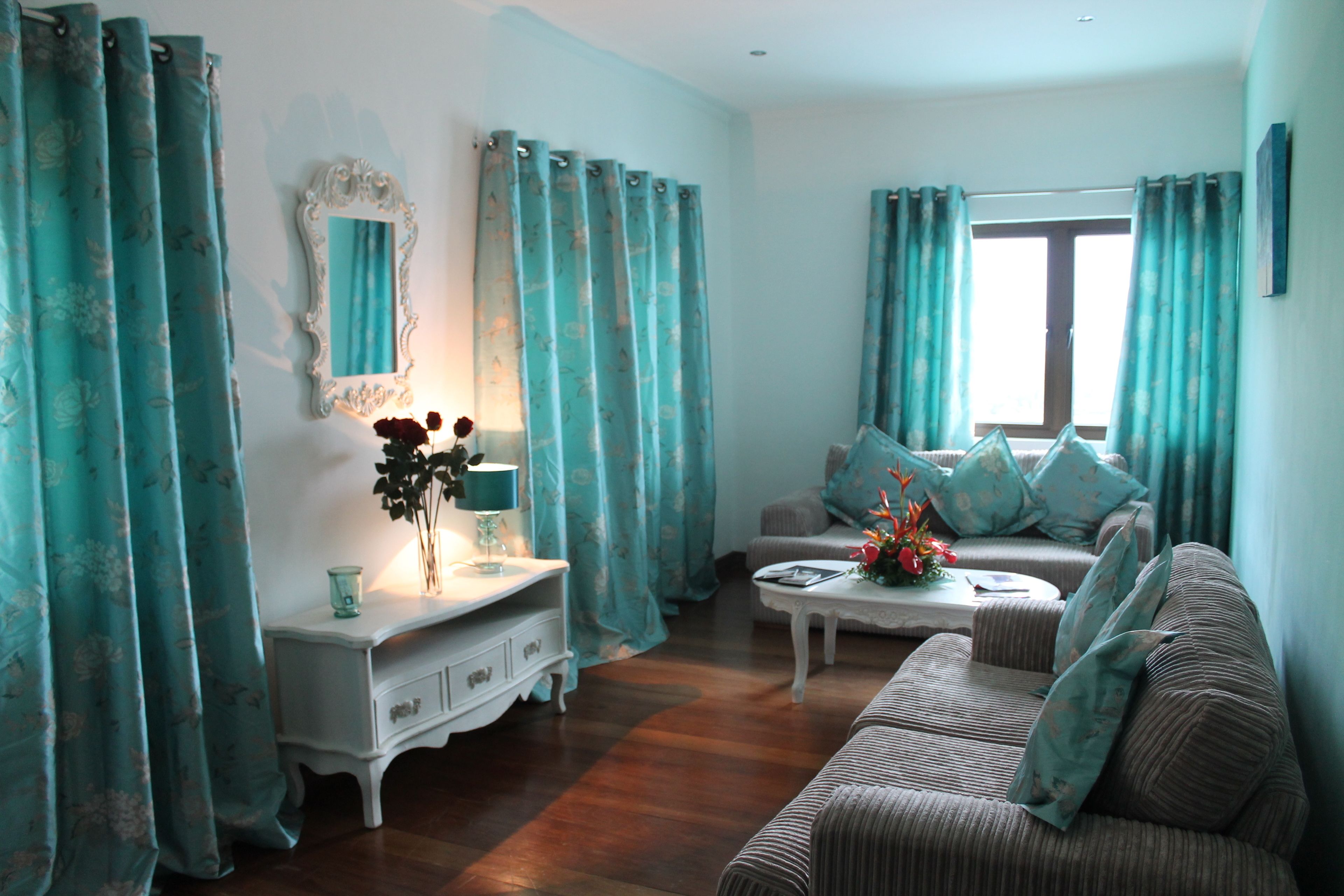 A living room with a sofa, a coffee table, a white dresser, and a mirror.