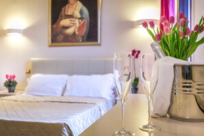 A hotel room with a neatly made bed, a vase with pink tulips, and two champagne flutes on a table. - Monna Clara Affittacamere (Florence)