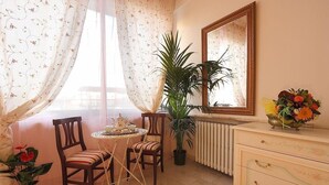 A room with a dining table, chairs, a radiator, a potted plant, a mirror, and a dresser with drawers. - Monna Clara Affittacamere (Florence)