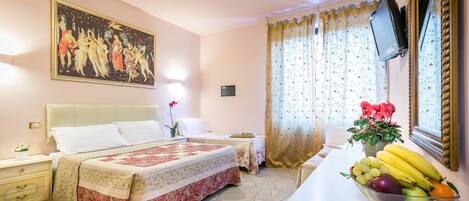 Habitación de hotel con dos camas, un cuadro grande en la pared, un frutero sobre la mesa y un televisor montado en la pared.