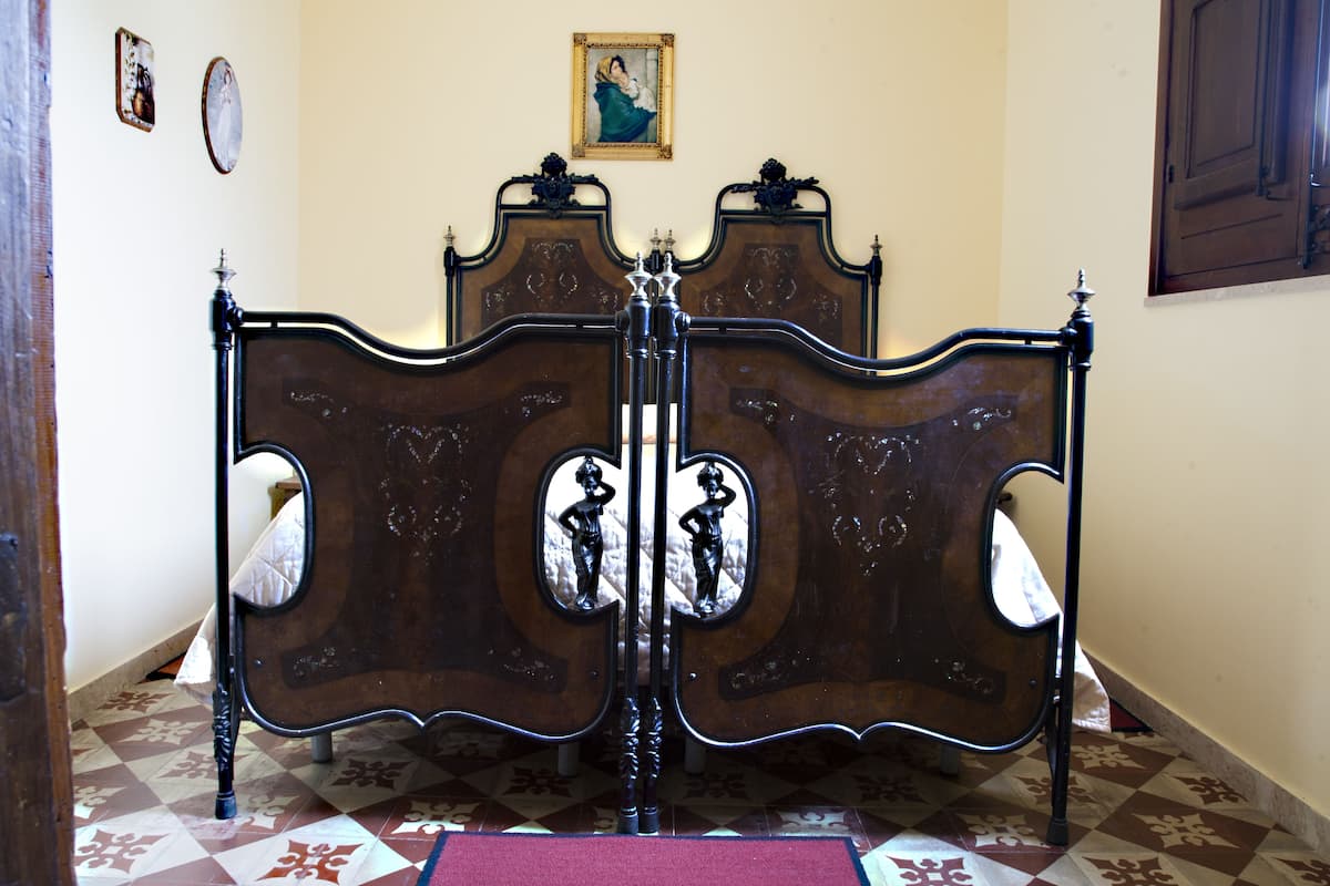 A room with a large, ornate bed with a wooden frame and a mirror in the center.