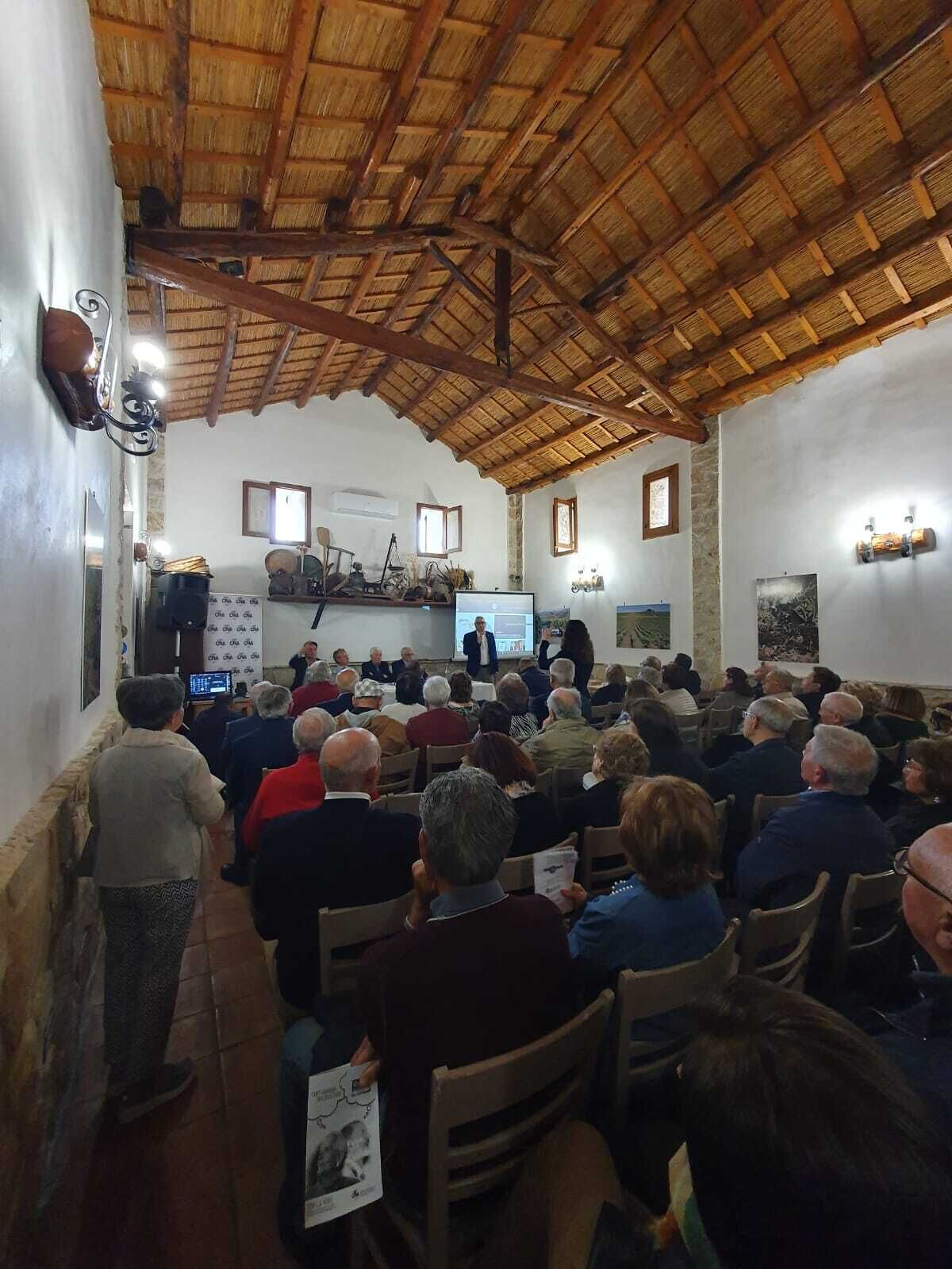 Ein Konferenzraum mit Holzboden und Steinwänden, ausgestattet mit einem Projektor und einer Leinwand für Präsentationen.