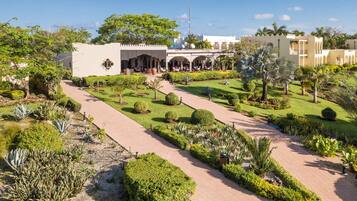 Stroll through the serene garden to the hotel, featuring a traditional architectural style with arches and a symmetrical layout.