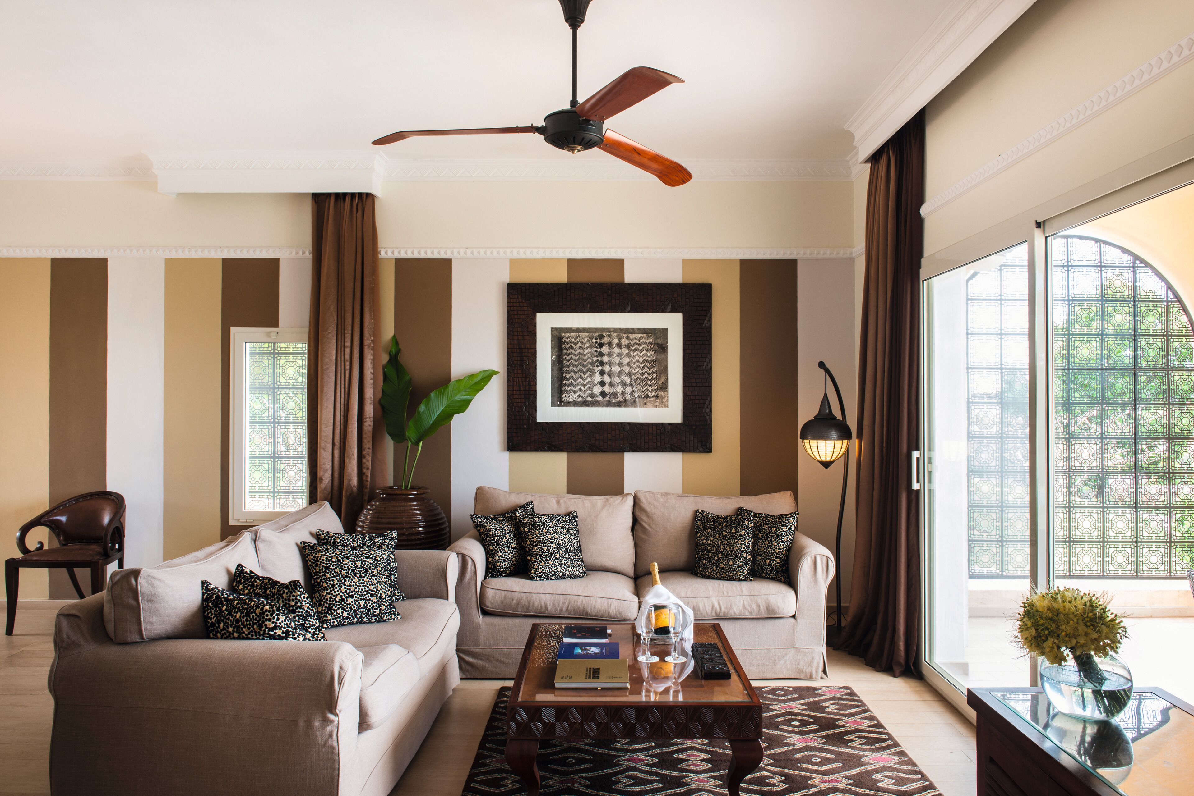 A living room with two sofas, a coffee table, a ceiling fan, and a large window with curtains.