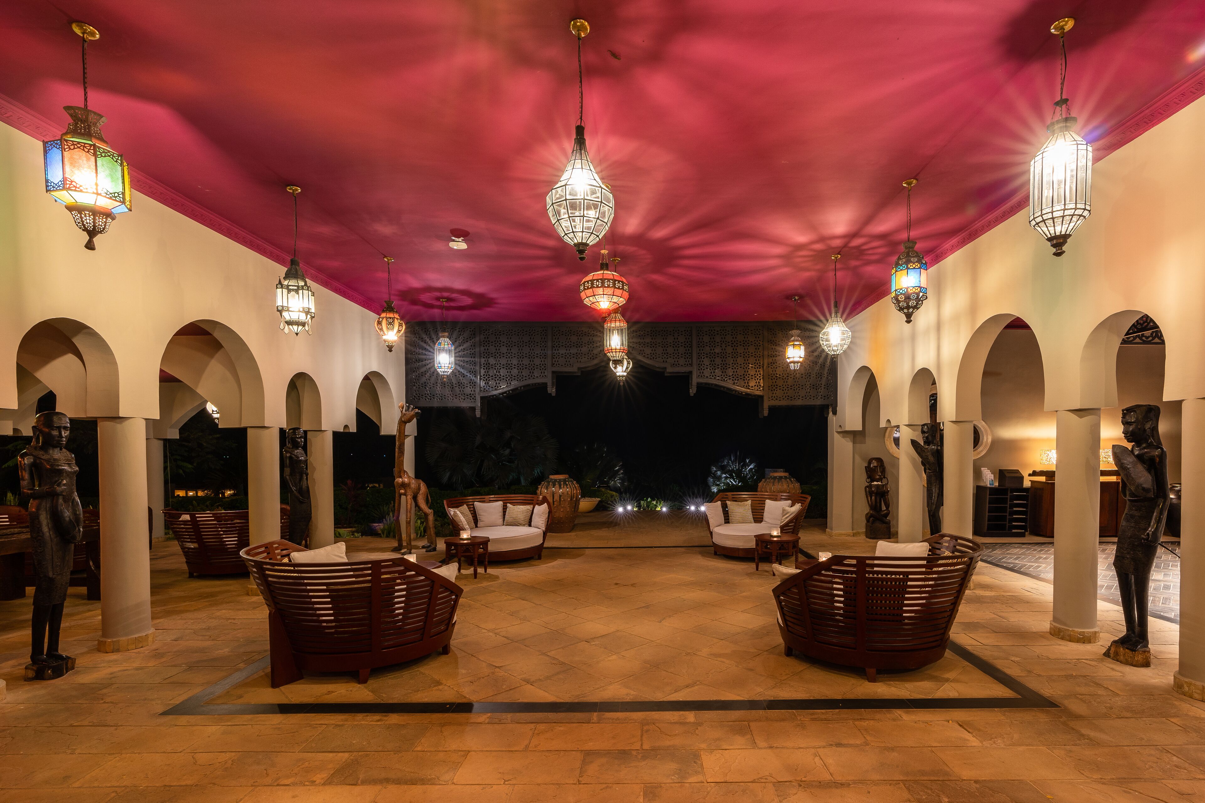 An indoor courtyard with multiple seating areas, hanging lanterns, and statues.