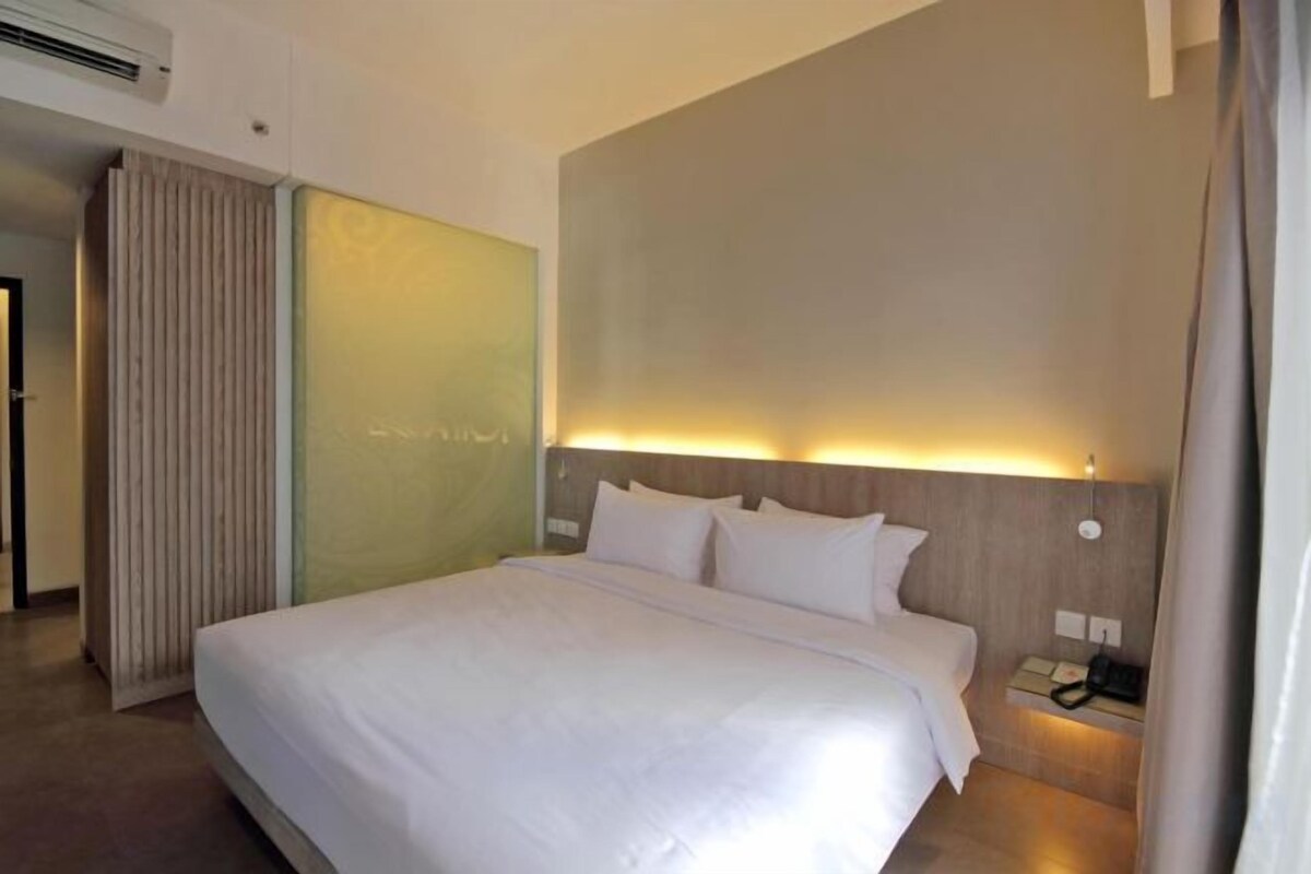 A hotel room with a large bed, a bedside table, and a wall-mounted phone.