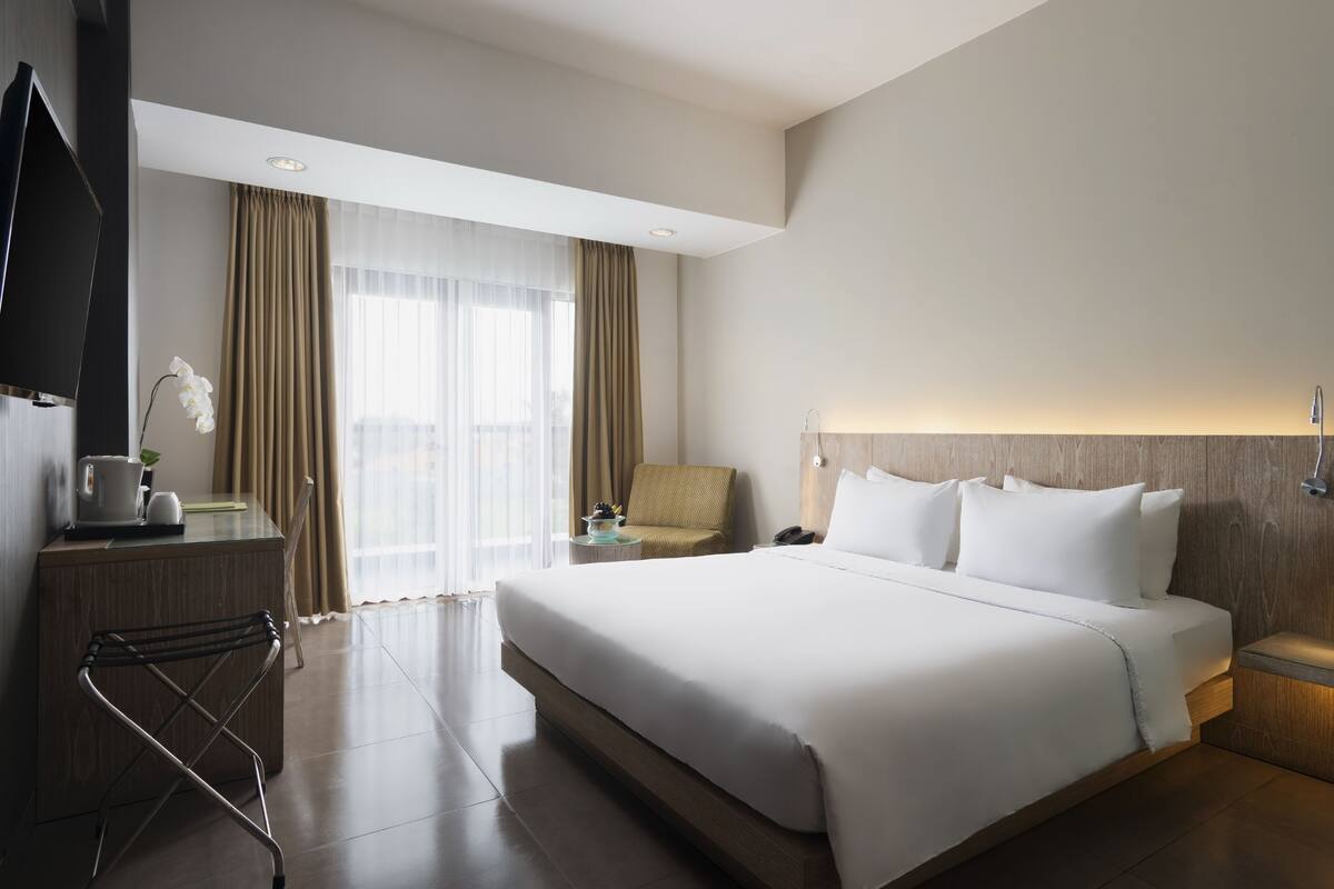 Une chambre d’hôtel moderne avec un grand lit, une télévision, un bureau avec une lampe et une chaise.