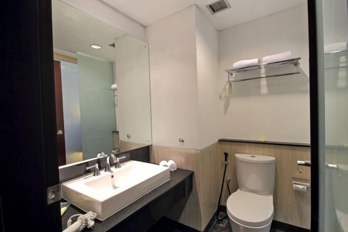 Une salle de bain moderne équipée d’un lavabo, d’un miroir, de toilettes et d’un porte-serviettes.