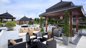 Un área de lounge al aire libre con arreglos de asientos, estructuras cubiertas y plantas en macetas.