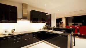 Una cocina moderna con gabinetes negros, una campana extractora de acero inoxidable y un comedor con sillas rojas.