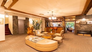 A spacious lobby with a curved seating area, a reception desk, and a staircase leading to an elevator. - Villa Alpen (Yamanouchi)