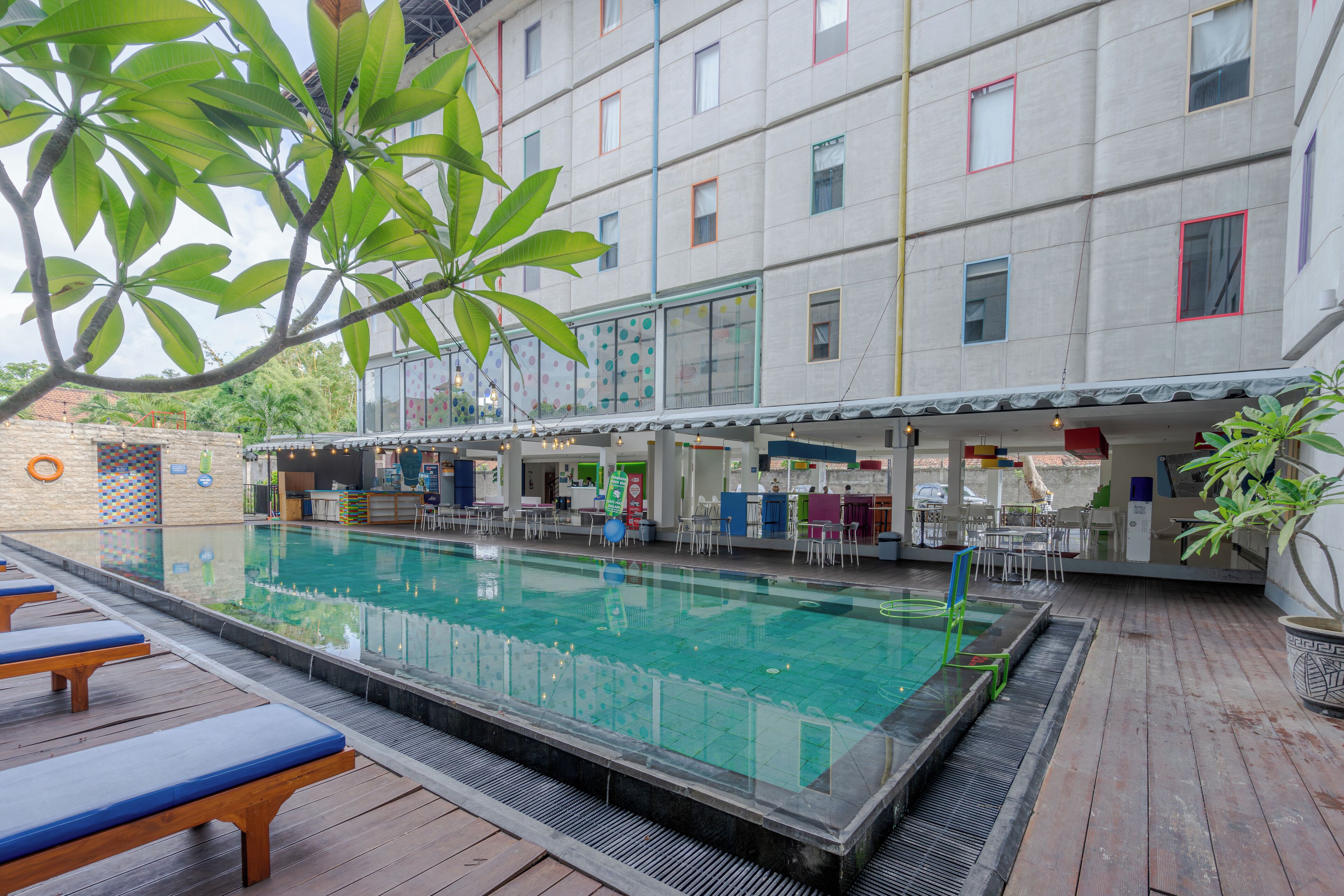 A swimming pool with lounge chairs and a bar area in a modern building.