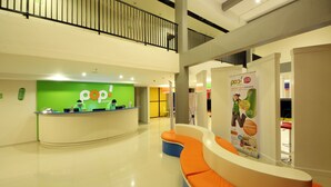 A hotel lobby with a reception desk, seating area, and a staircase. - POP! Hotel Kuta Beach Bali (Kuta)