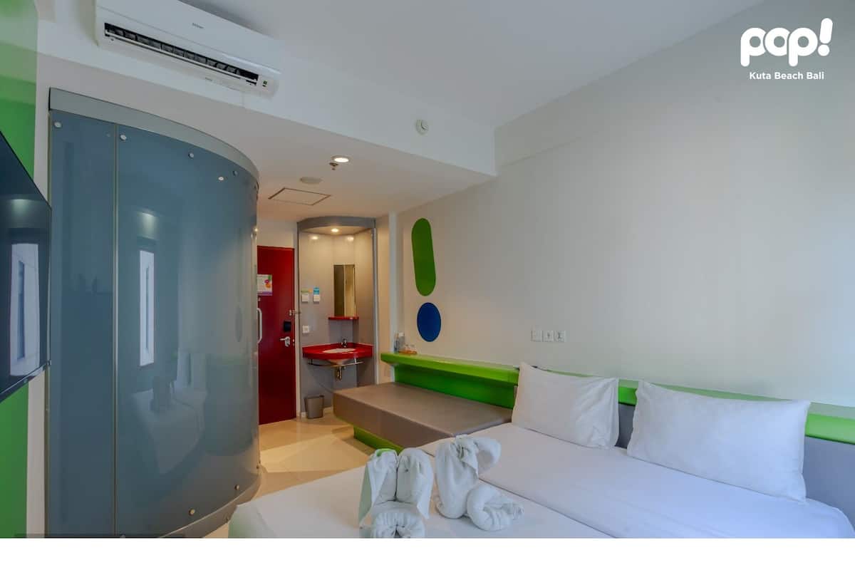 A modern hotel room with a bed, a large wardrobe, a bathroom with a sink, and a mirror.