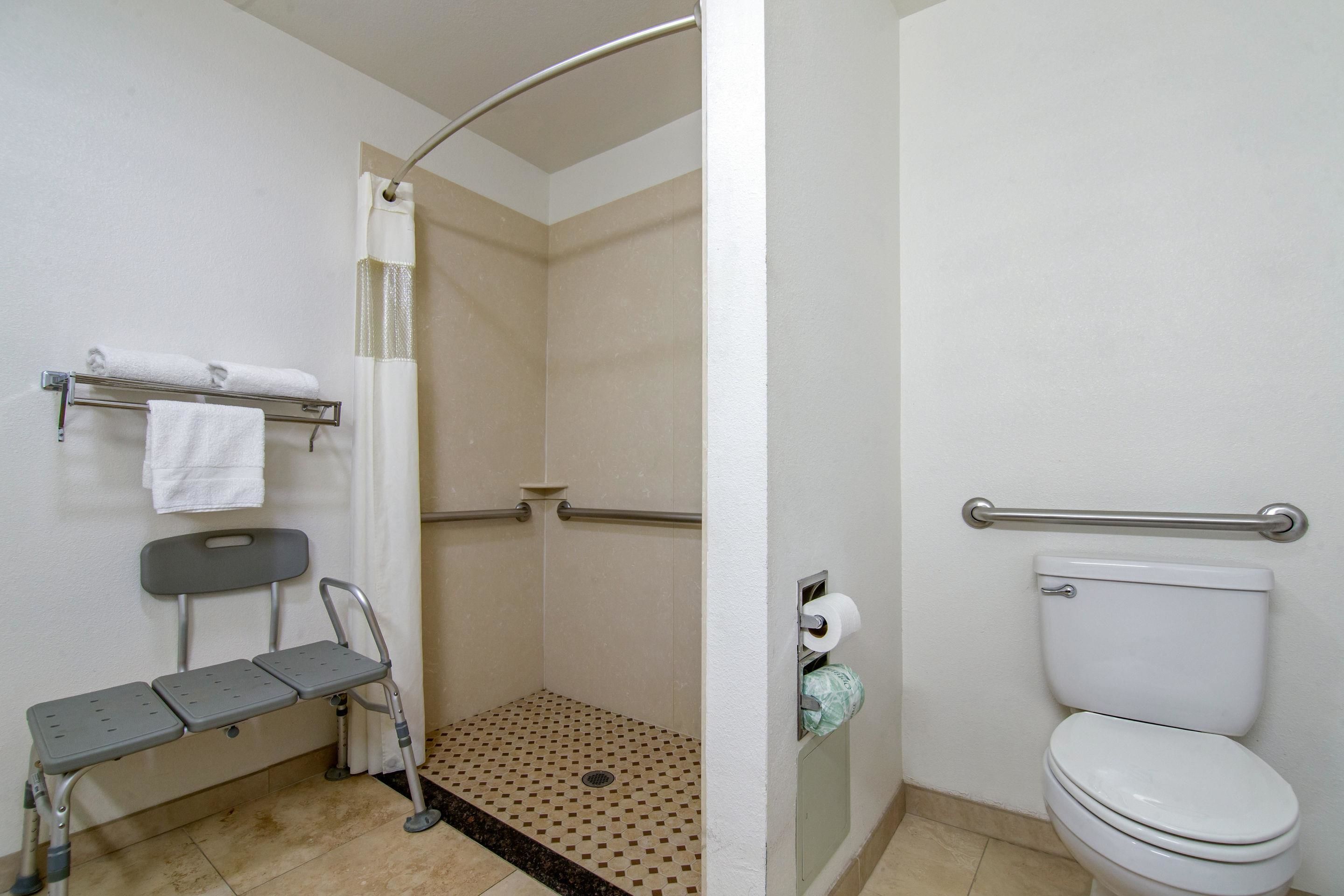 Une salle de bain équipée d’une douche, de toilettes, d’un banc et d’un porte-serviettes.