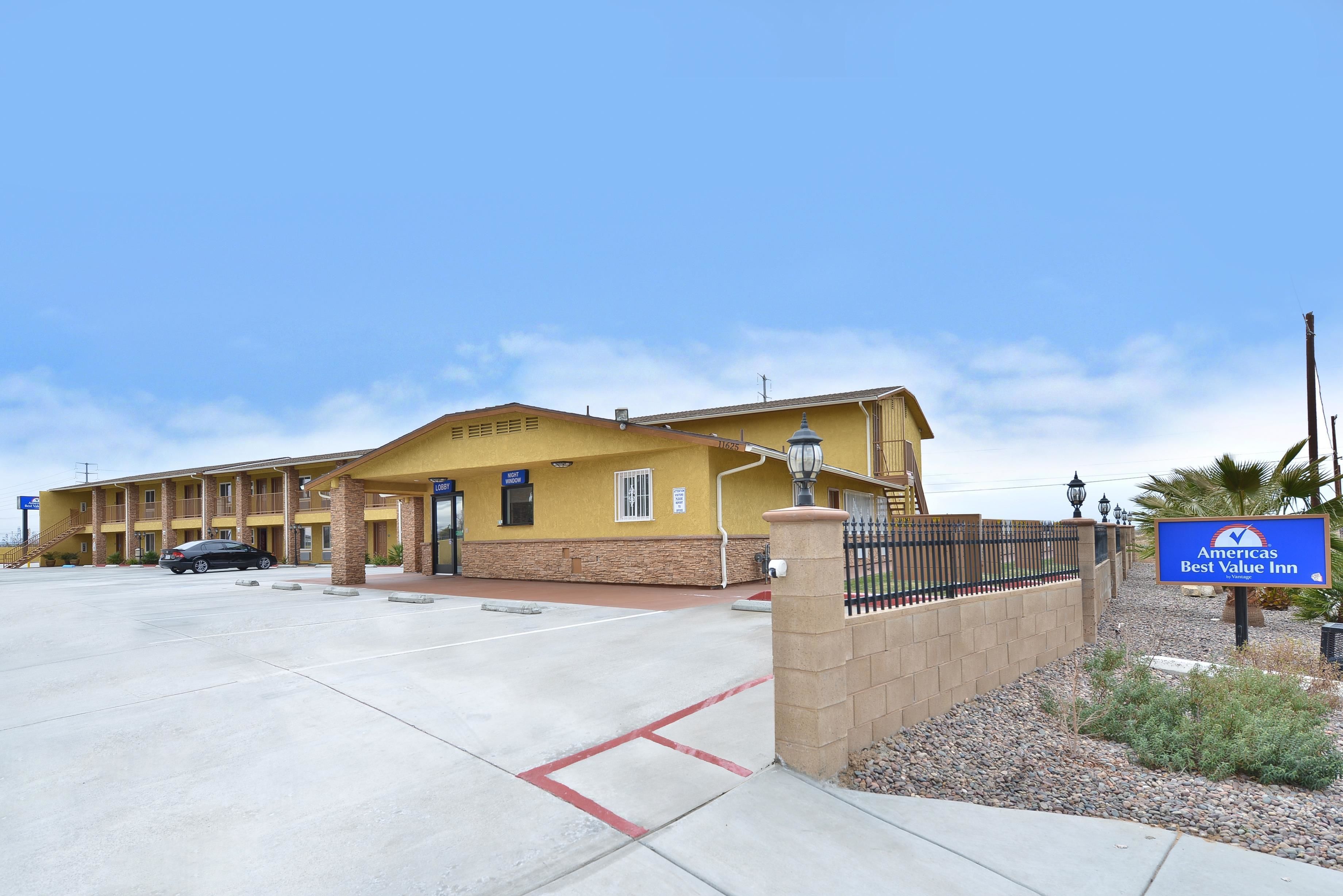A motel with a yellow facade, a gated entrance, and a sign indicating it is the Americas Best Value Inn.