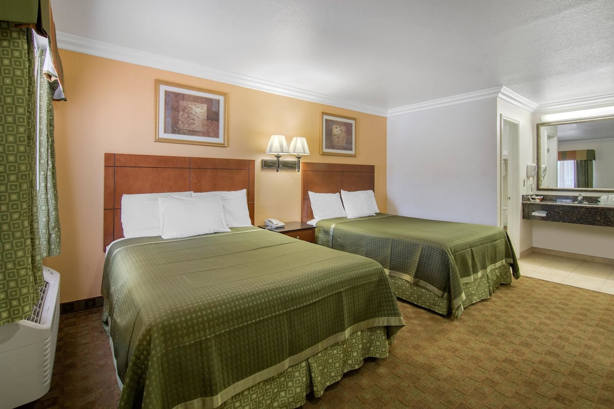 A hotel room with two beds, a bathroom, and a large mirror.