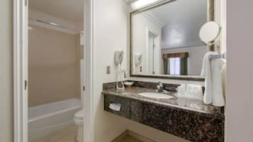 A bathroom with a bathtub, a sink, a mirror, and a towel rack.