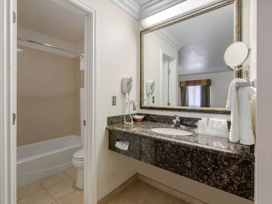 A bathroom with a bathtub, a sink, a mirror, and a towel rack.