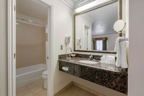 A bathroom with a bathtub, a sink, a mirror, and a towel rack.