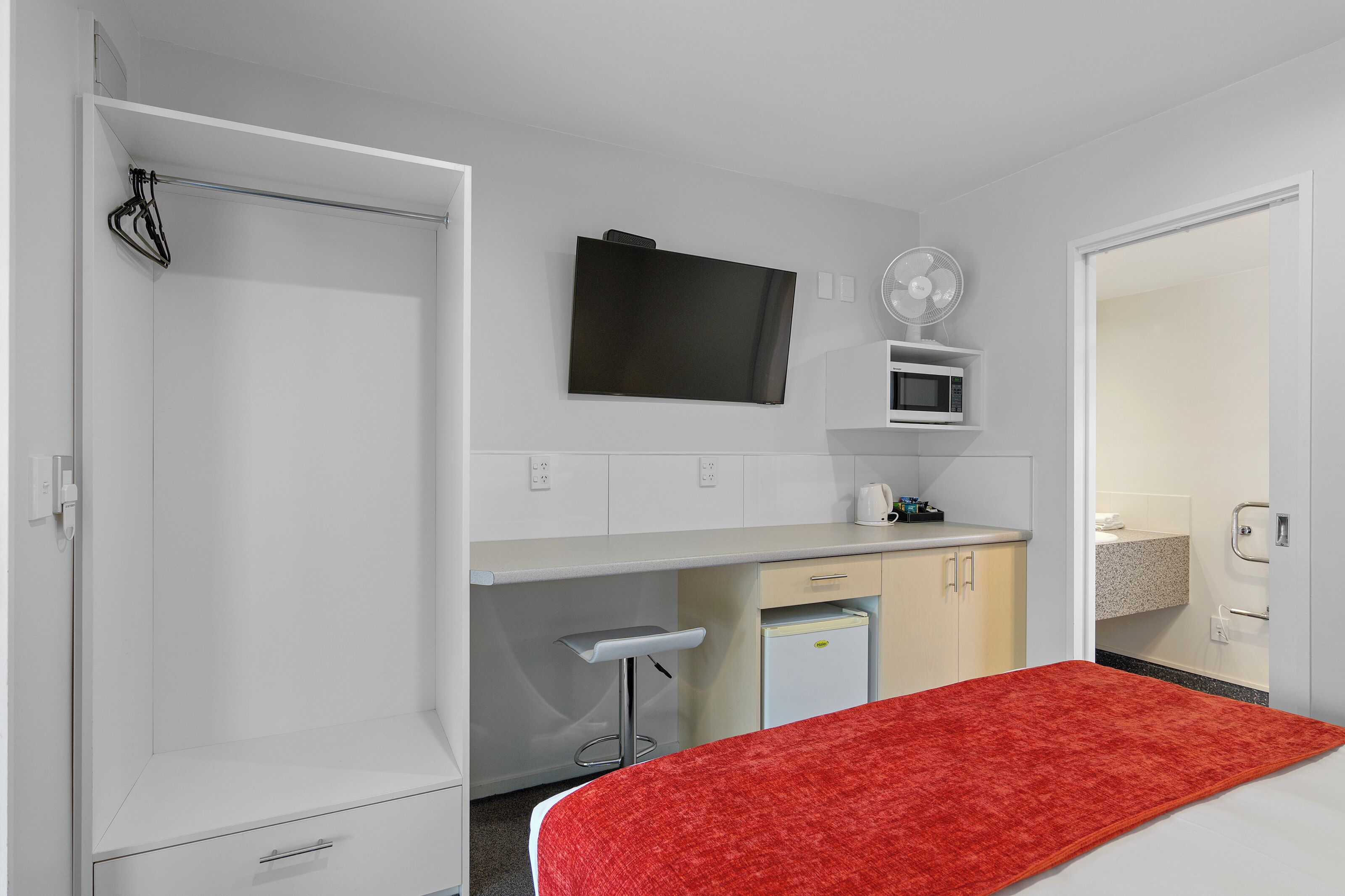 Een knus hotelkamer met een bed, een kitchenette, een televisie en een badkamer.
