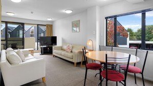 A modern living room with a sofa, TV, and dining area.