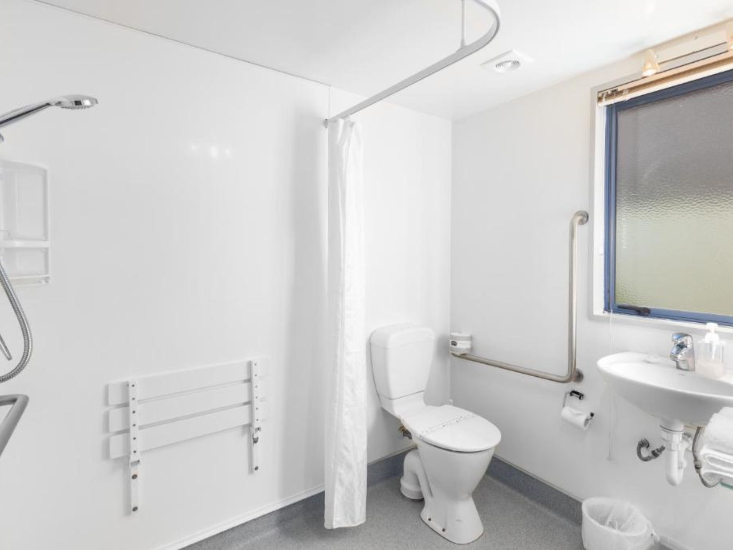 A modern bathroom with a toilet, shower, and sink.