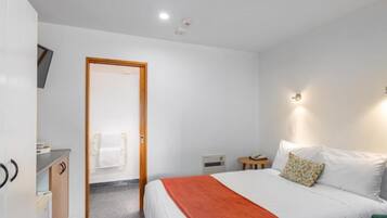 Une chambre d’hôtel comprenant un lit, un bureau, une chaise, une petite table et un téléviseur.