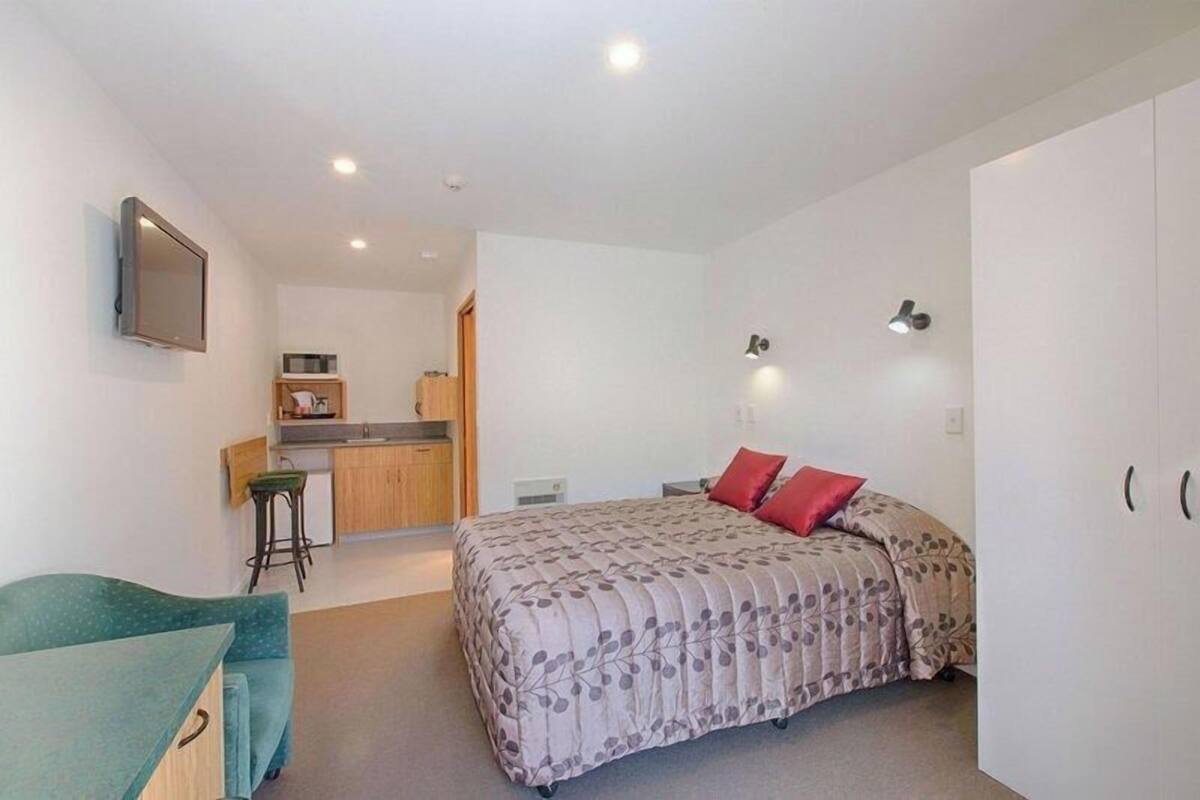 Une chambre avec un lit, un bureau et un coin cuisine.