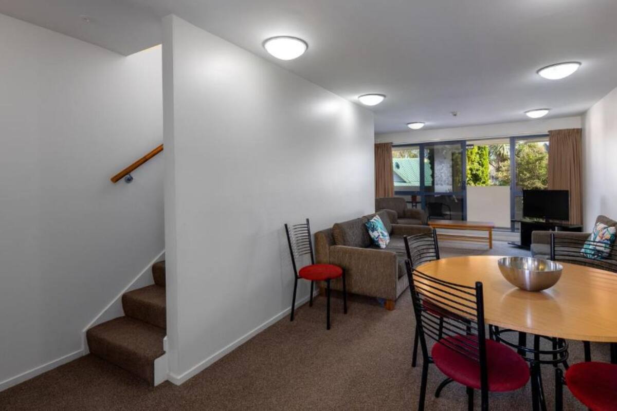 Un salon moderne avec un escalier, un coin repas et un téléviseur.