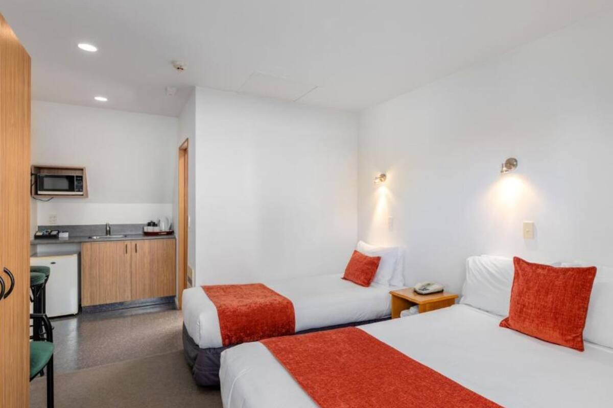 Une chambre d’hôtel avec deux lits, une kitchenette et un petit coin salon.