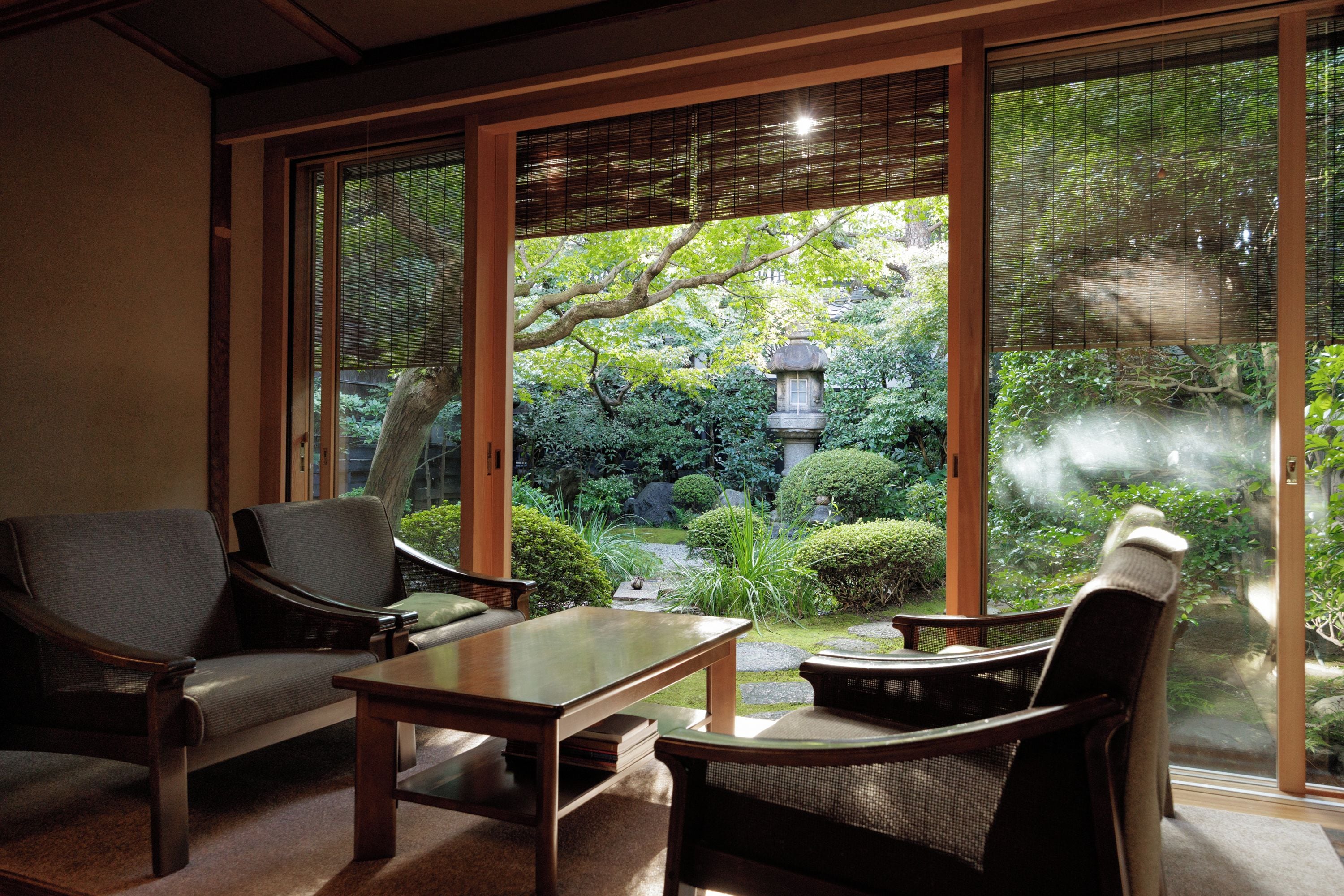 A traditional Japanese room with tatami flooring, a low table, and two chairs.