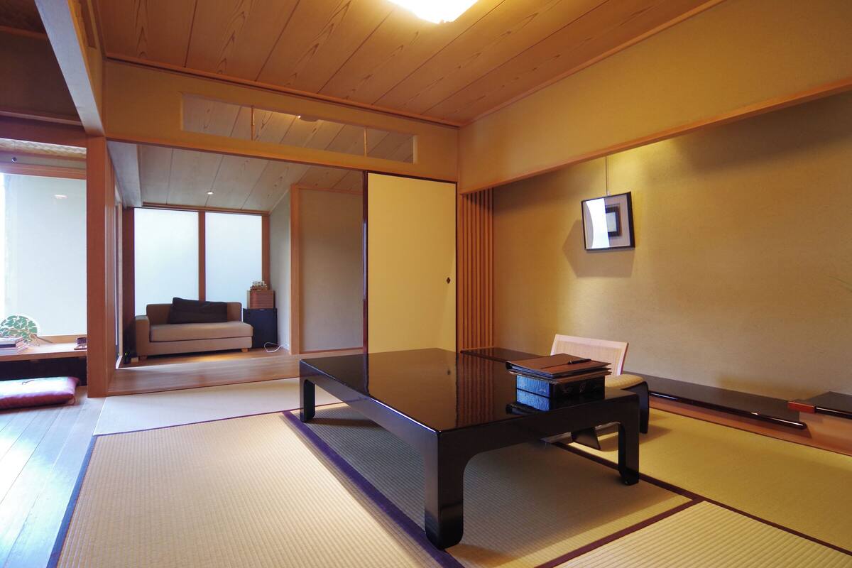 Une pièce de style japonais traditionnel, avec un sol recouvert de tatamis, une petite table basse et une porte coulissante donnant sur une autre pièce.