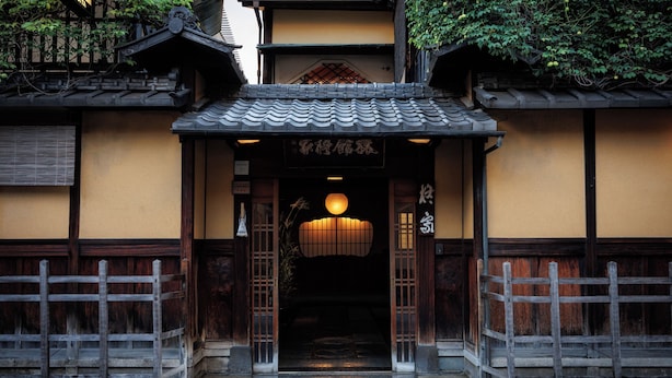 A traditional Japanese building entrance with a tiled roof, wooden gates, and a hanging lantern. - Hiiragiya (Kyoto)